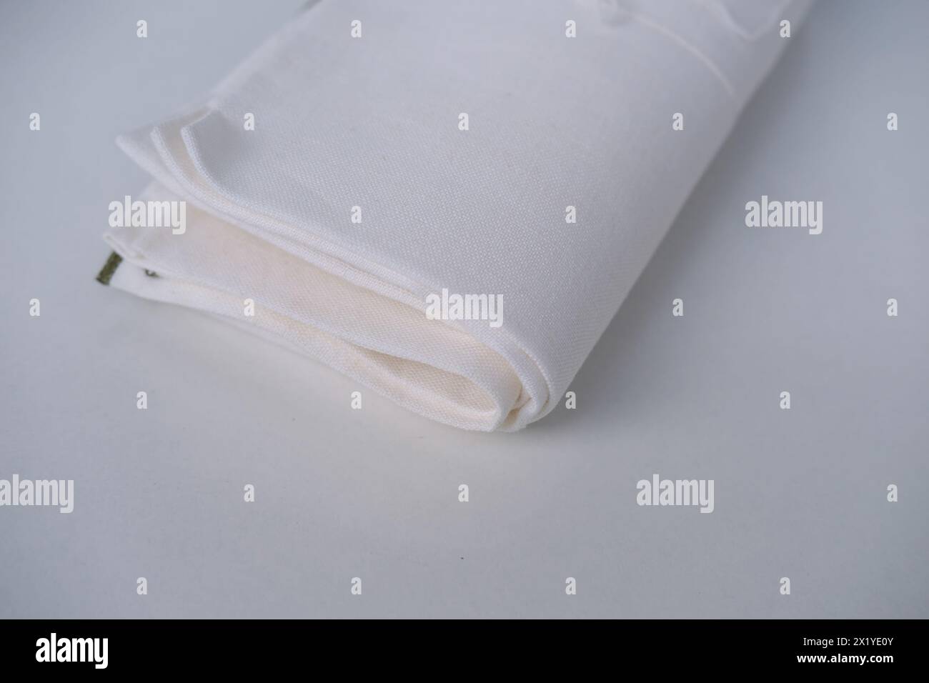 tissu de lin blanc, la serviette est enroulée en plusieurs couches, repose sur un fond clair, le concept de tissu écologique naturel Banque D'Images