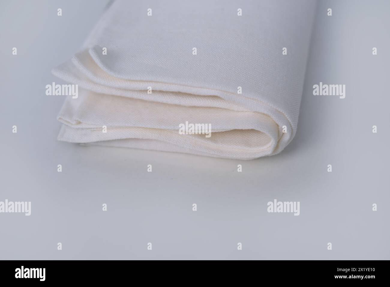 tissu de lin blanc, la serviette est enroulée en plusieurs couches, repose sur un fond clair, le concept de tissu écologique naturel Banque D'Images