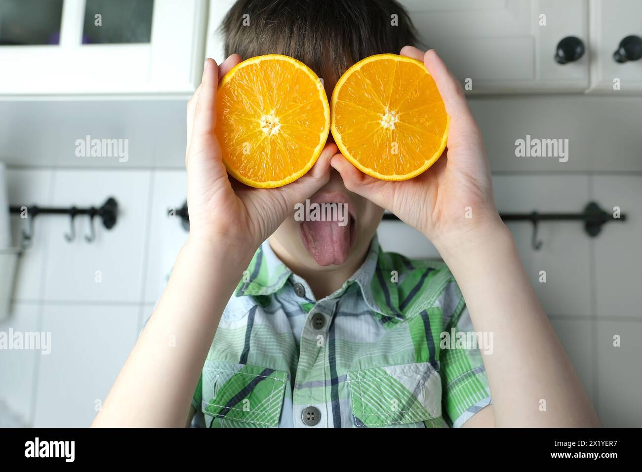 enfant, enfant 8-10, garçon assis dans la cuisine à la maison, oranges jaunes juteuses au lieu des yeux, gros plan de la tête, concept de régime alimentaire pour enfants, nourriture saine Banque D'Images