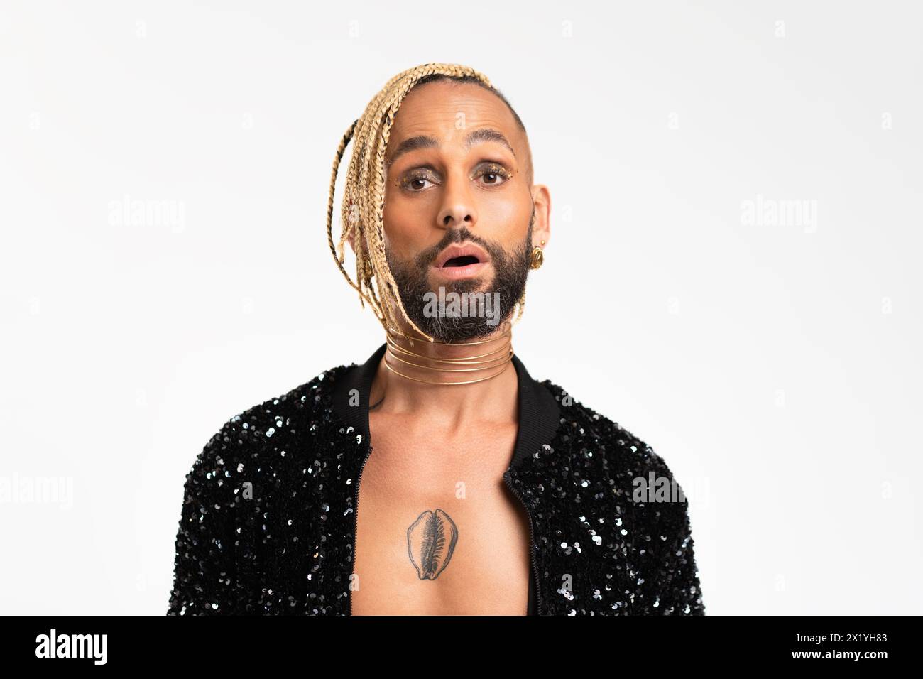 Homme gay noir confiant avec maquillage surpris isolé sur fond blanc, veste noire habillée avec sequins. Dégage un sentiment de fierté et d'individualité. Pouvoir de diversité du style personnel Banque D'Images