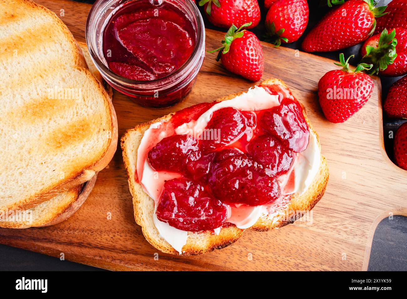 Tranche de pain grillé recouverte de confitures de fraises maison et fromage à la crème : tranches de pain blanc grillé et confitures de fraises maison et Neufchatel Banque D'Images