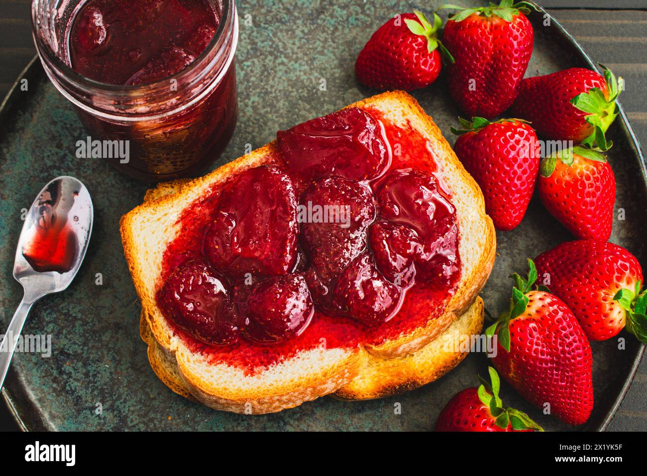 Tranche de pain grillé recouverte de confitures de fraises maison : pain blanc tranché et grillé et confitures de fraises maison avec de gros morceaux de fruits Banque D'Images