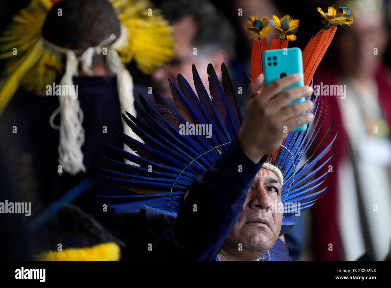 An Indigenous representative takes a photo as he waits for the start of the closing ceremony of the 1st Ordinary Meeting of the National Council for Indigenous Policy, in Brasilia, Brazil, April 18, 2024. (AP Photo/Eraldo Peres) Banque D'Images