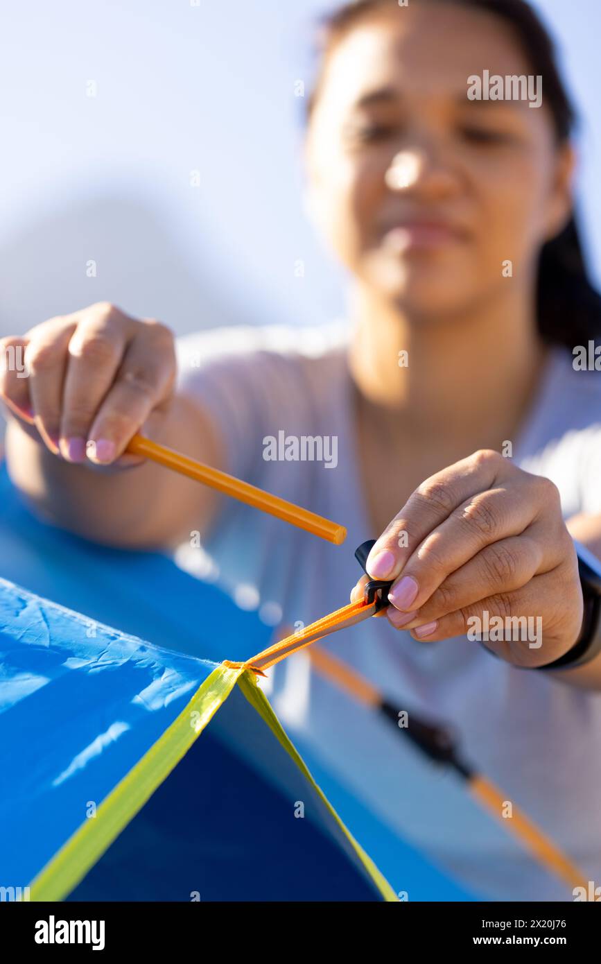 Randonneur féminin biracial installant la tente, se concentrant sur la nature de l'aventure de tâche Banque D'Images