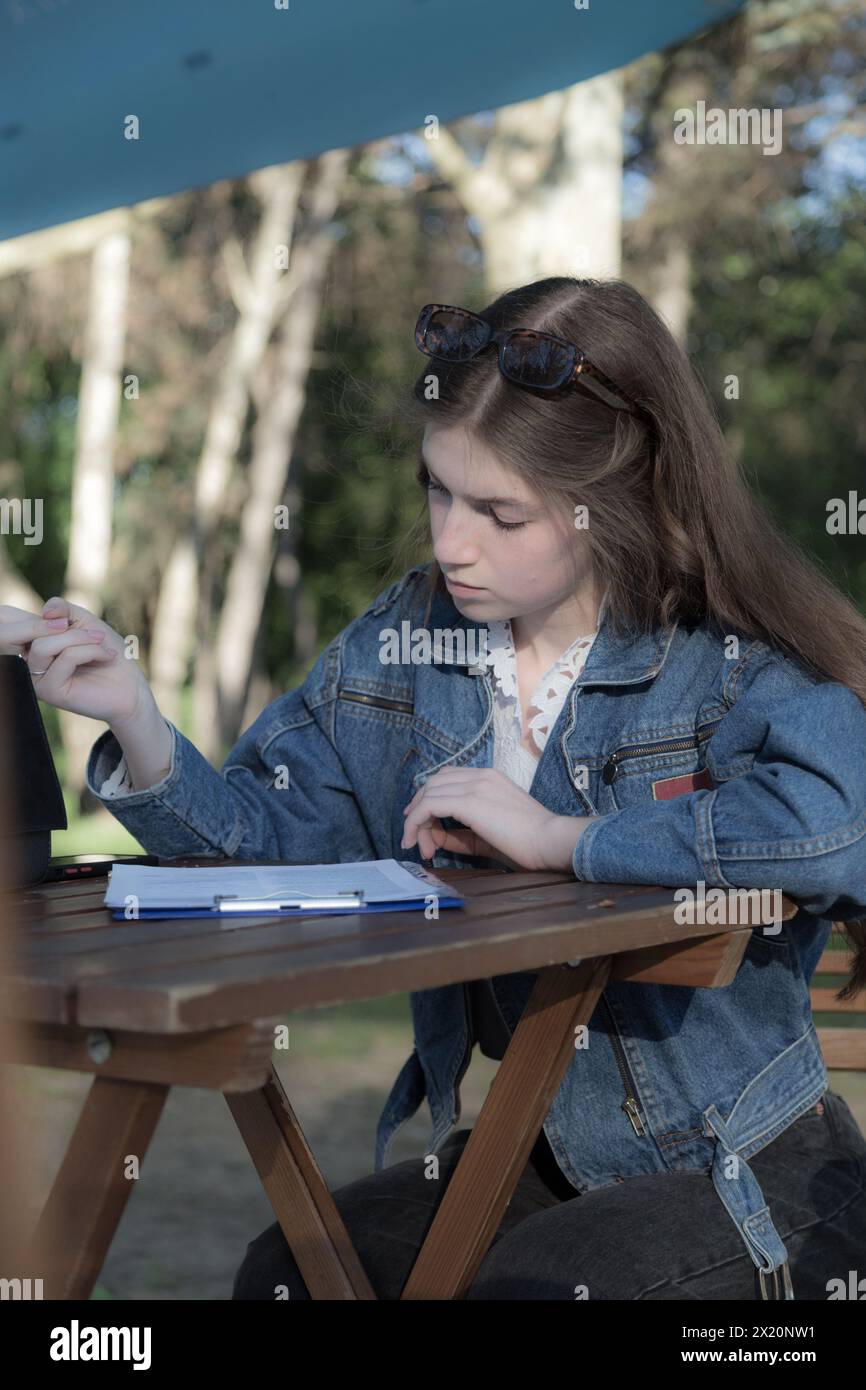 Une belle fille écrit quelque chose. Ça se passe quelque part dans le parc. Gros plan. Banque D'Images