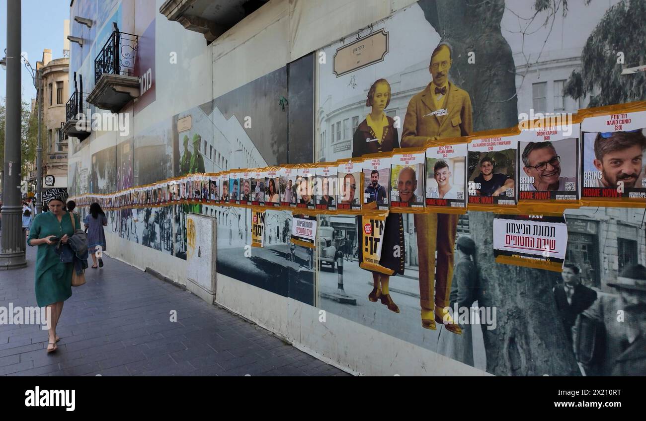 Les piétons passent devant des affiches avec des images d’otages israéliens détenus à Gaza sur la route de Jaffa le 19 avril 2024 à Jérusalem. Israël Banque D'Images