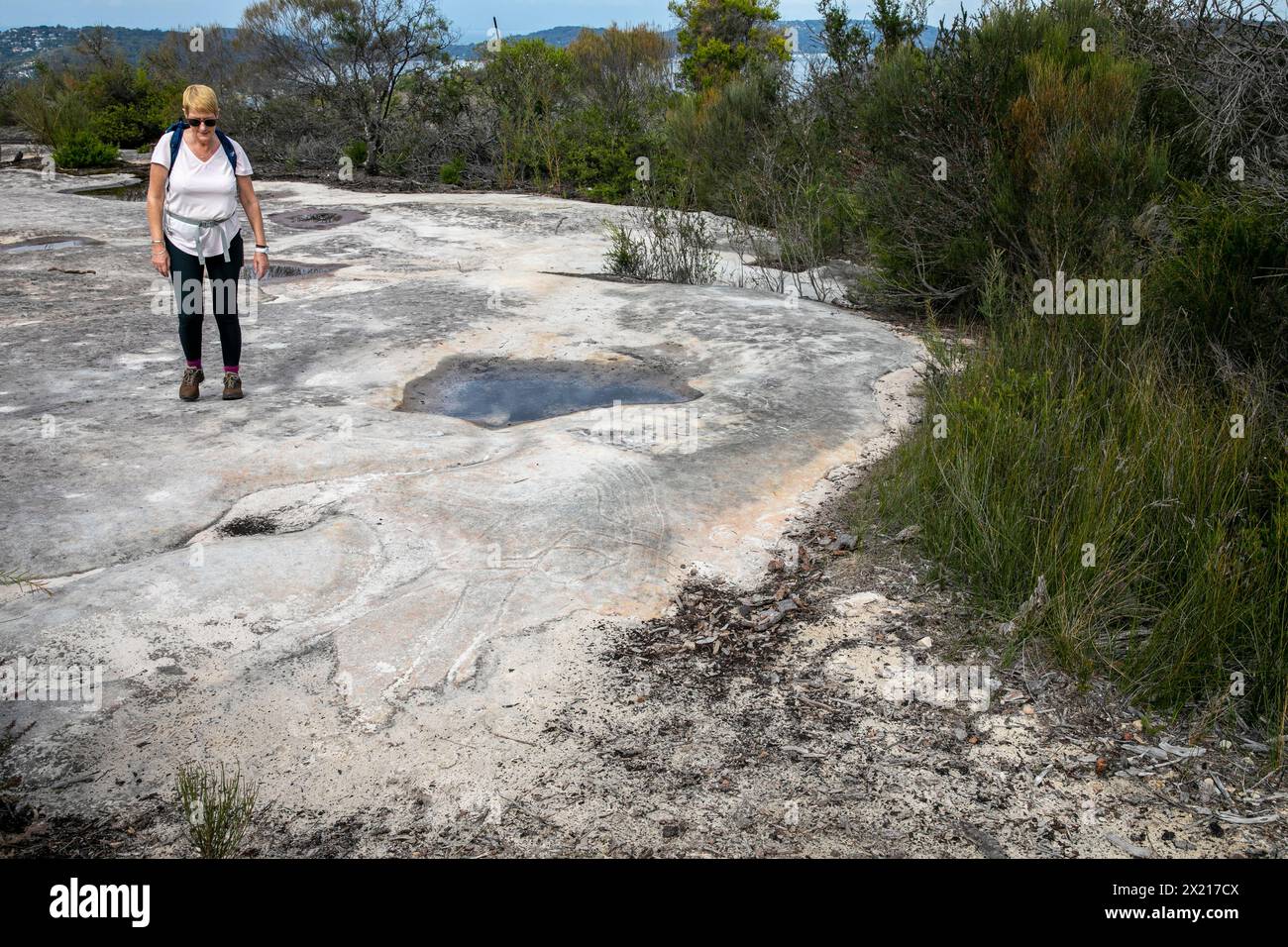 Art rupestre autochtone des premières Nations autochtones dans le parc national de Ku-Ring-Gai Chase, modèle libéré femme voit l'art, Sydney, Nouvelle-Galles du Sud, Australie Banque D'Images