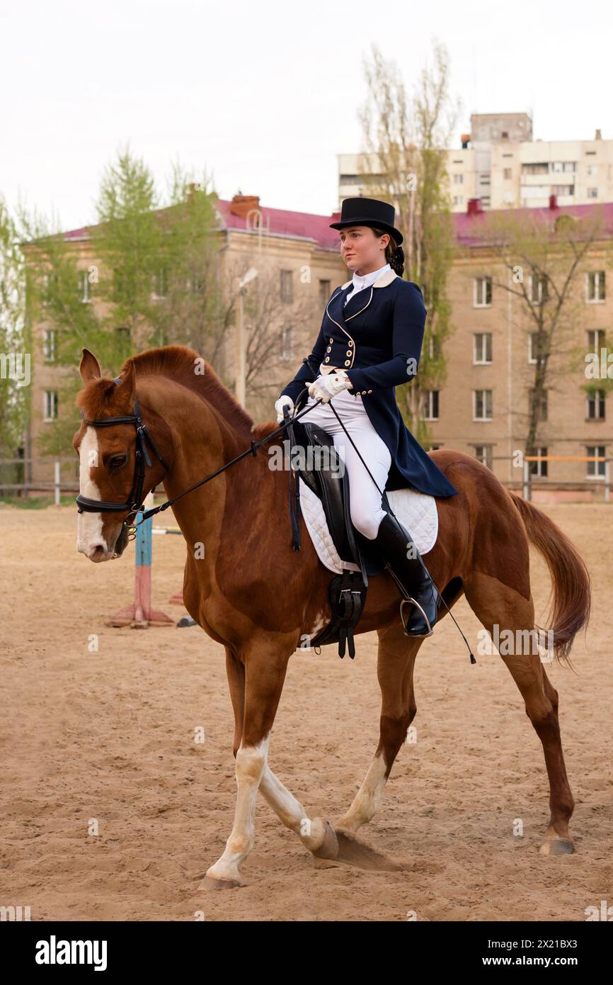 Un équestre en tenue habillée lors de l'entraînement en plein air. Séance d'équitation. Dressage. Jockey féminin en uniforme équitation équine. École d'équitation Banque D'Images