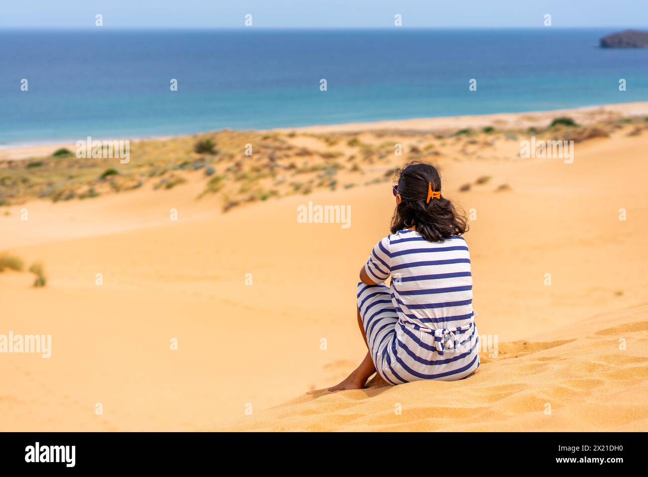 Vue arrière d'une femme au sommet d'une dune de sable regardant la mer Banque D'Images