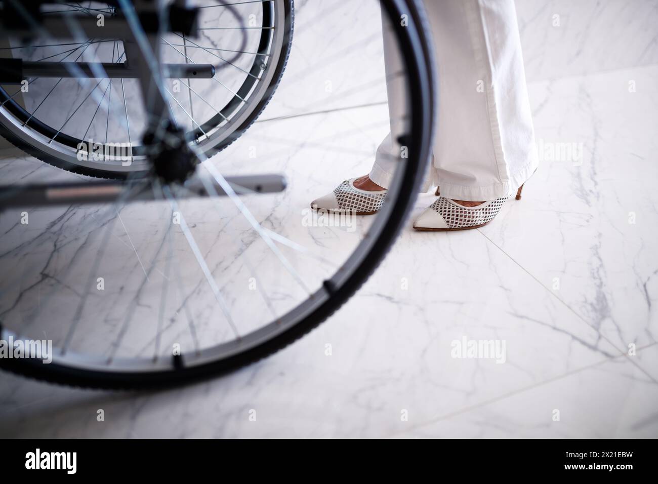 Pieds d'une femme poussant un fauteuil roulant Banque D'Images