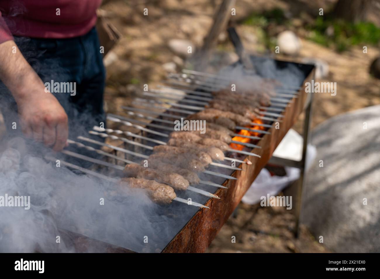 Un homme fait cuire de la viande sur un gril Banque D'Images