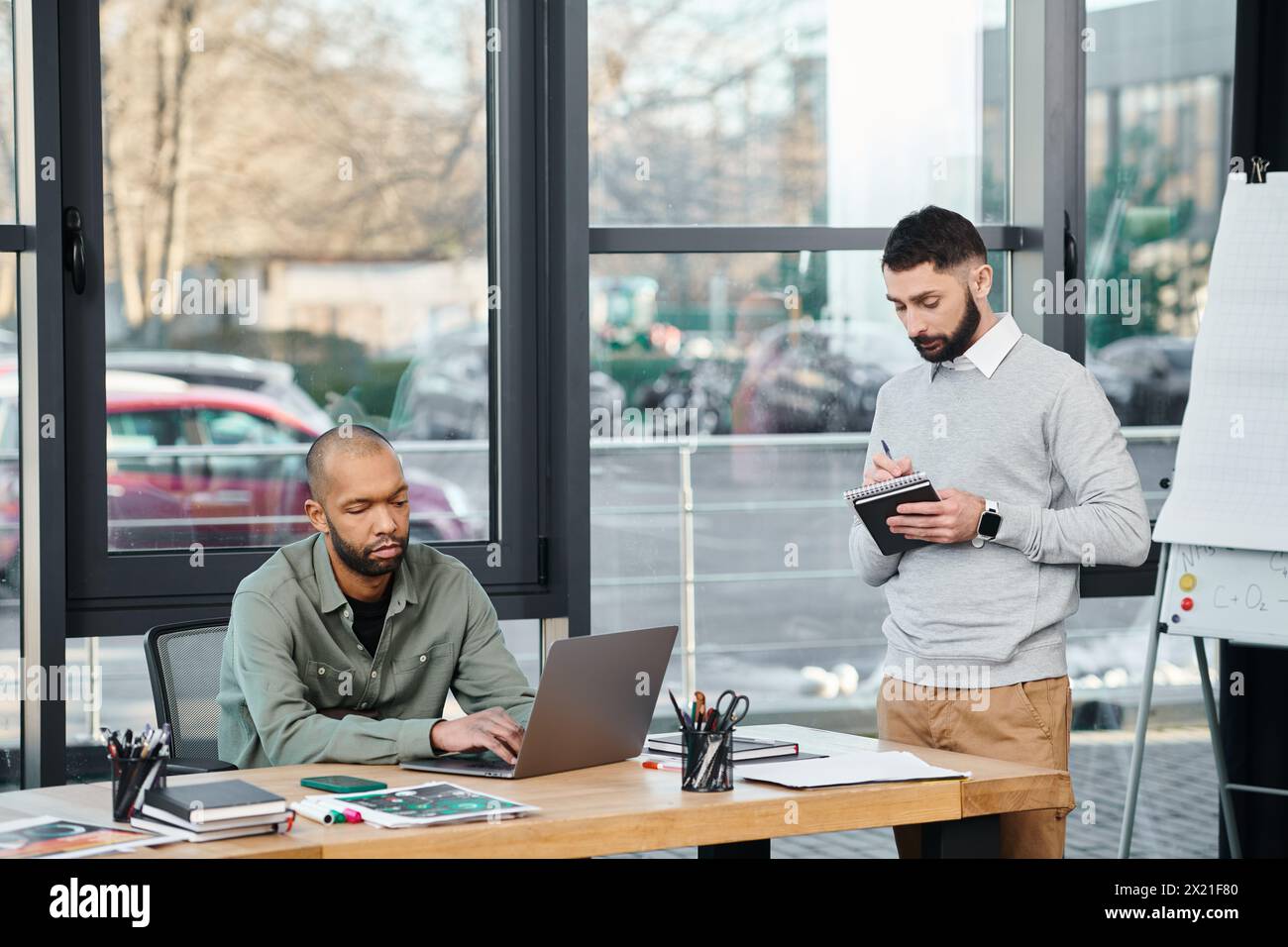 Deux hommes profondément imprégnés de leurs ordinateurs portables, engagés dans une session de codage collaboratif à une table de bureau moderne, la diversité et l'inclusion Banque D'Images