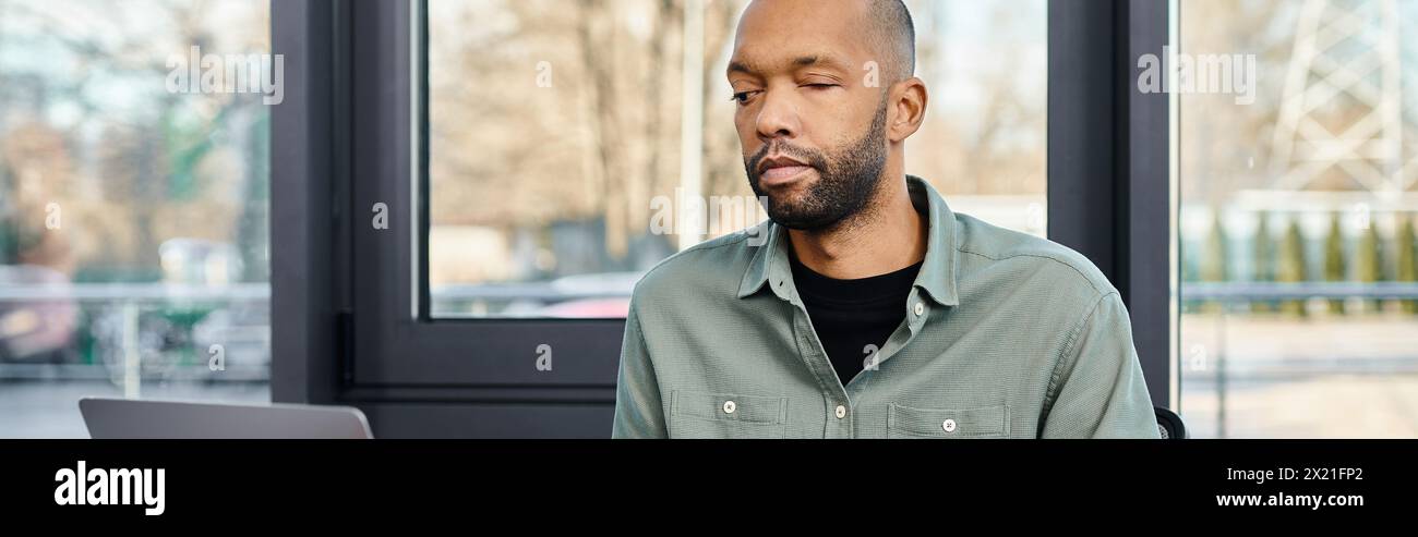 l'homme handicapé est assis attentivement devant un ordinateur portable, immergé dans le monde de la culture d'entreprise et des projets d'affaires. Banque D'Images