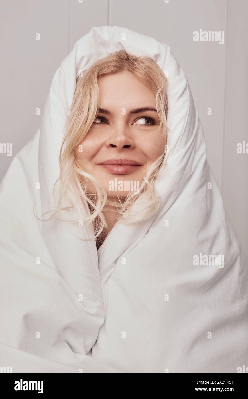 Femme d'âge moyen après le sommeil le matin avec une couverture Banque D'Images