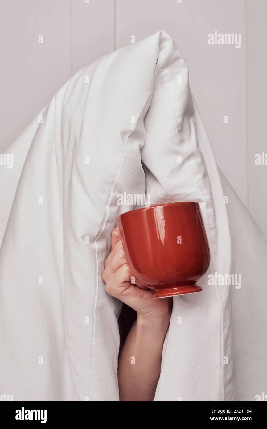 Femme tenant une tasse de café après le sommeil avec une couverture Banque D'Images