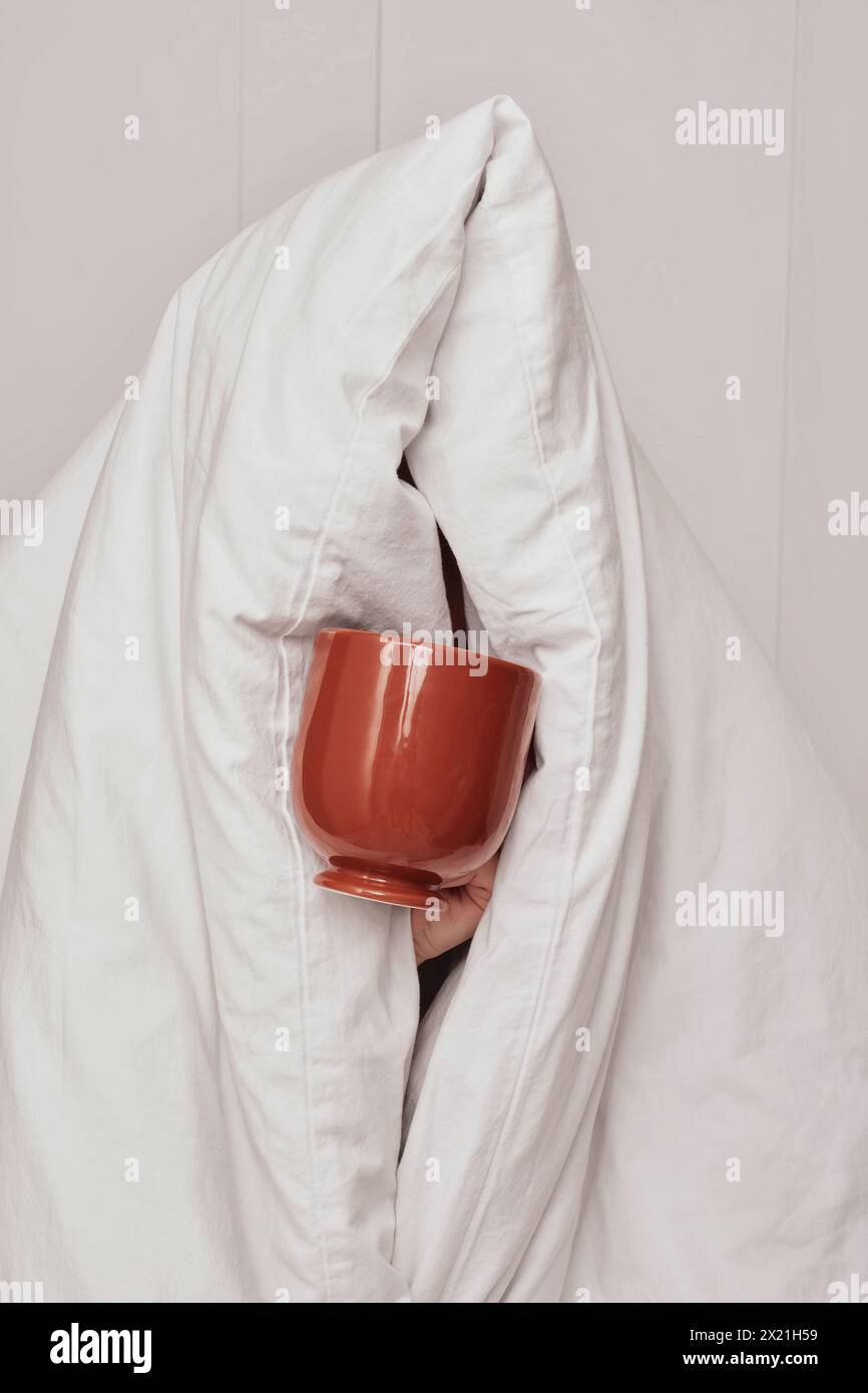 Femme tenant une tasse de café après le sommeil avec une couverture Banque D'Images