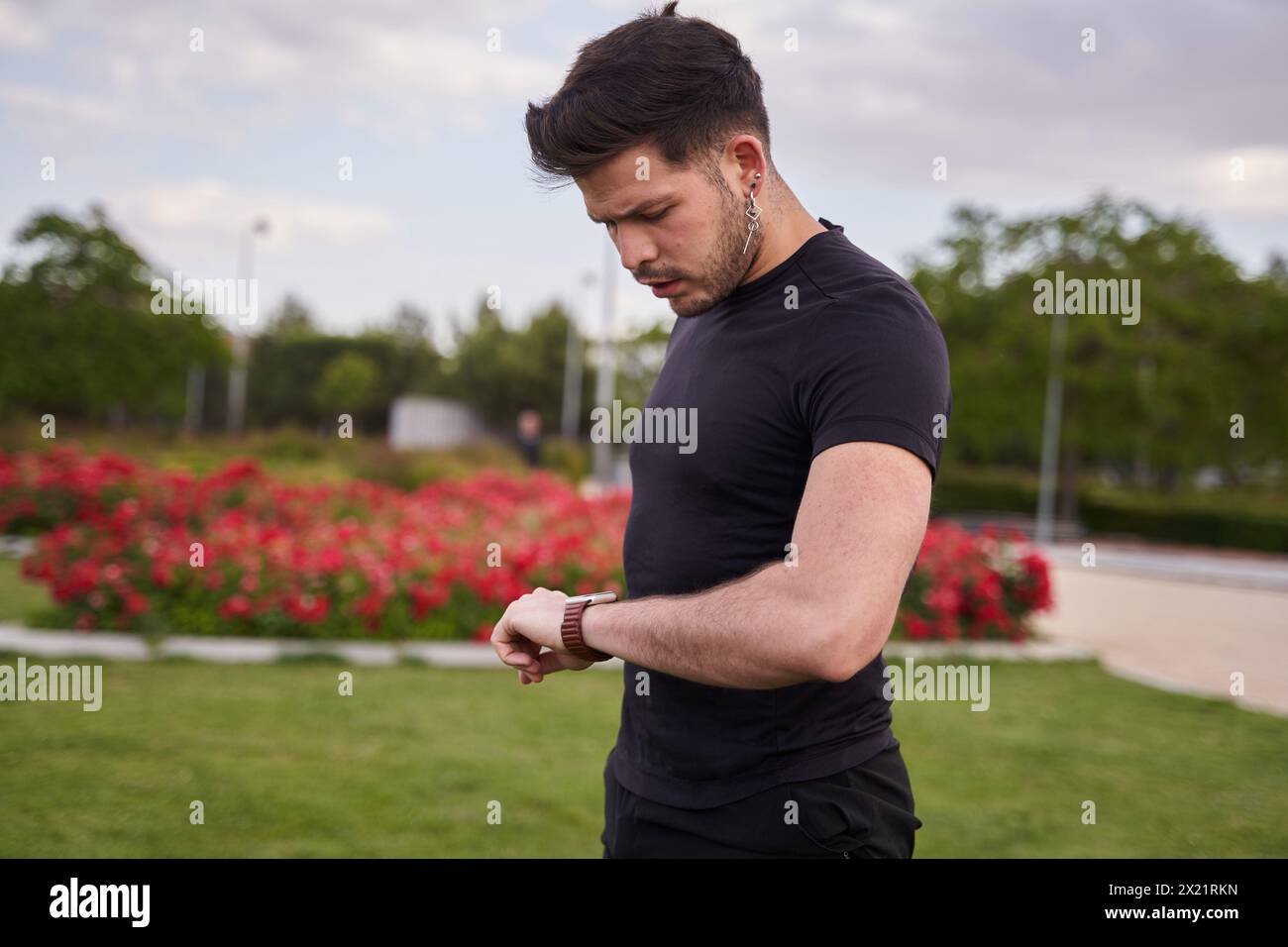 latino homme en sportswear regarde sa montre intelligente Banque D'Images