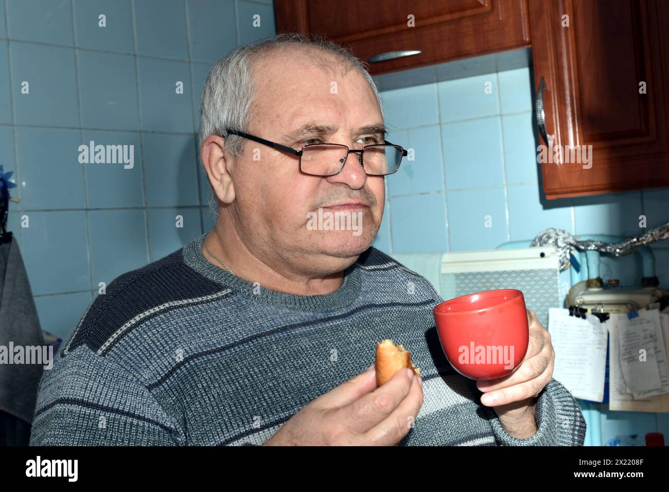 Portrait d'un homme tenant une tasse et un chignon dans ses mains, vue de profil. Banque D'Images