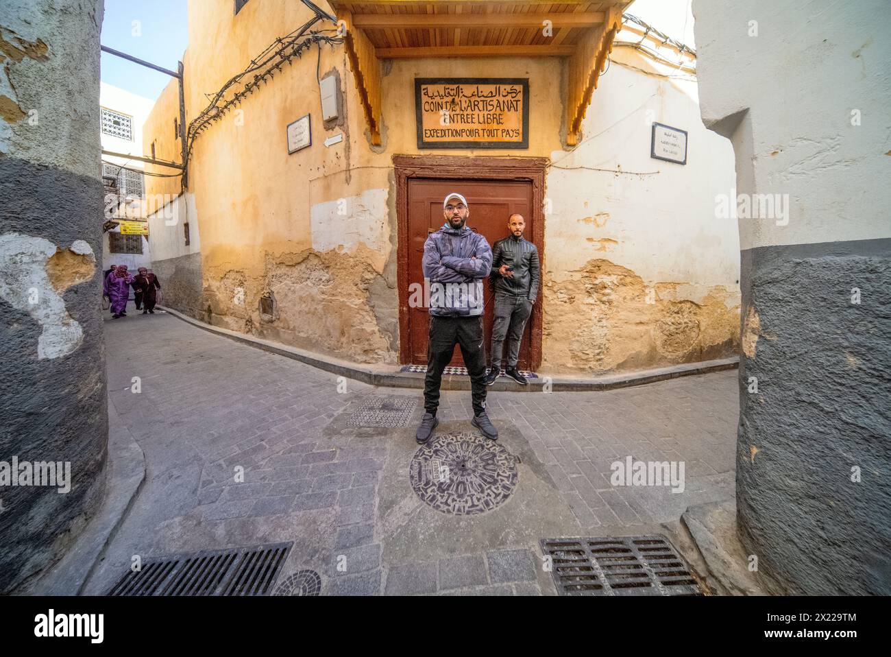 Deux jeunes gens se tiennent dans les rues étroites de Fezs antique Medina. Banque D'Images