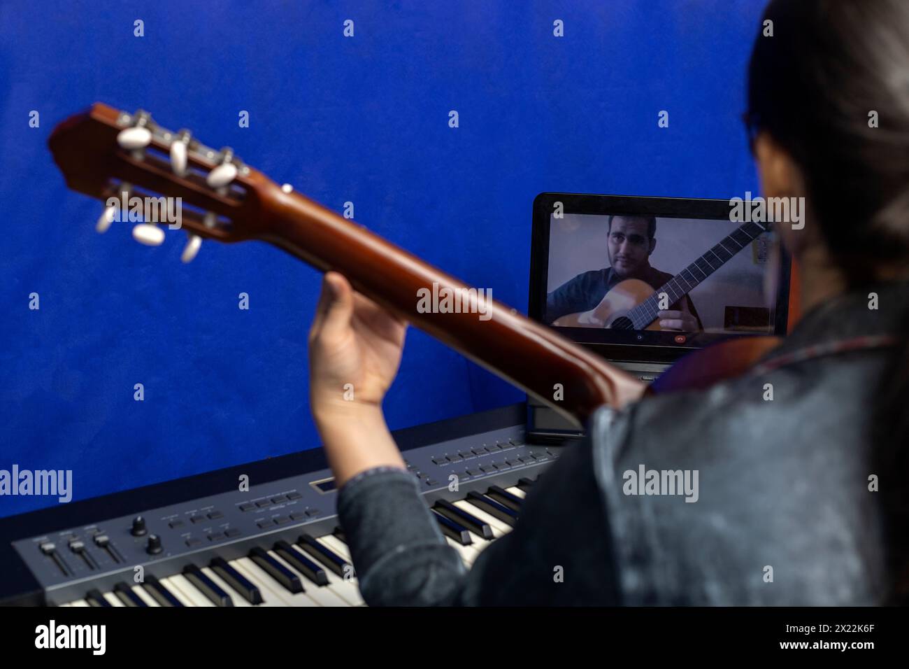 Jeune professeur latino-américain enseigne la guitare en ligne à l'aide d'un ordinateur portable. Concept de cours de musique à distance Banque D'Images