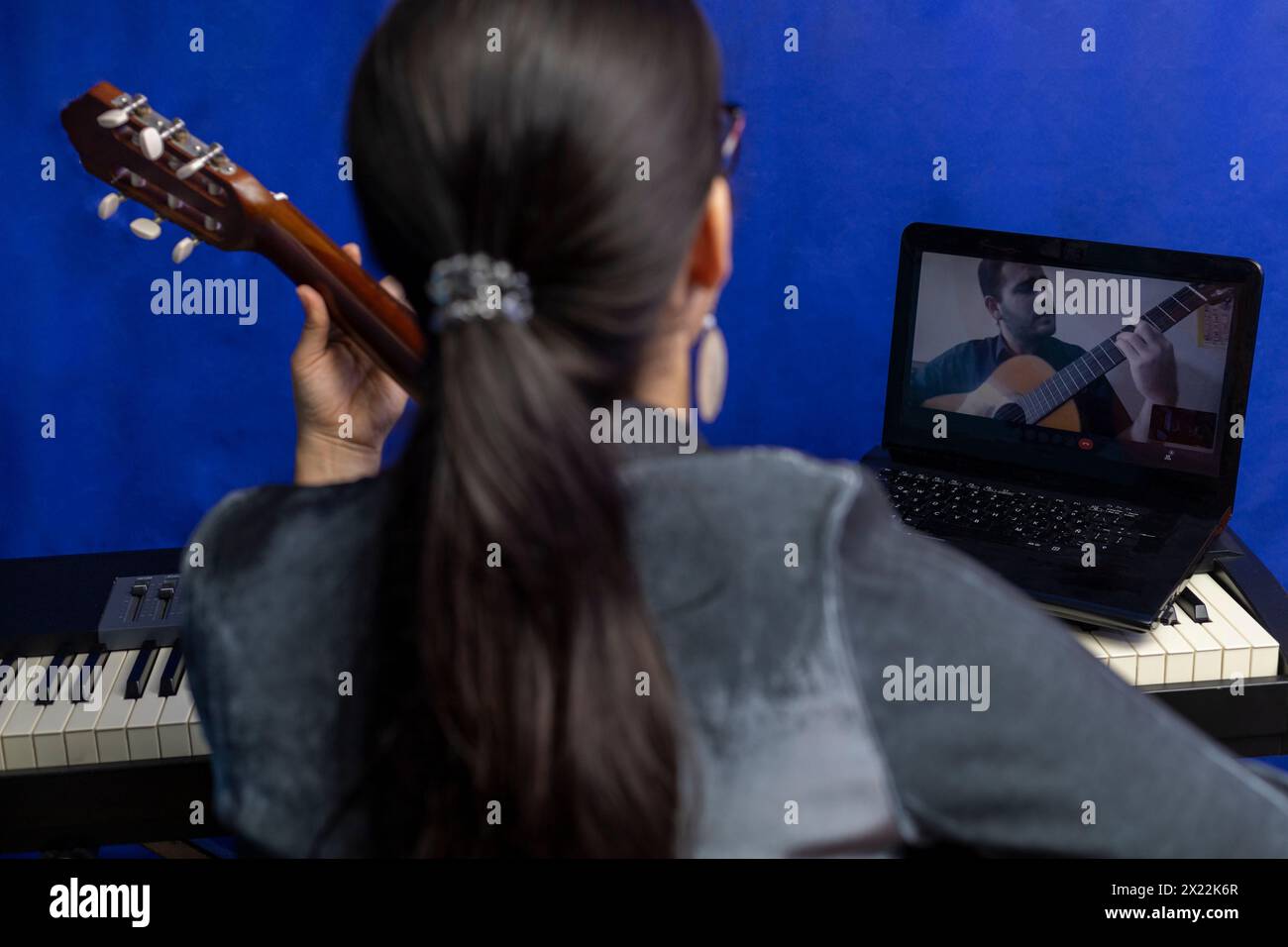 Jeune professeur latino-américain enseigne la guitare en ligne à l'aide d'un ordinateur portable. Concept de cours de musique à distance Banque D'Images