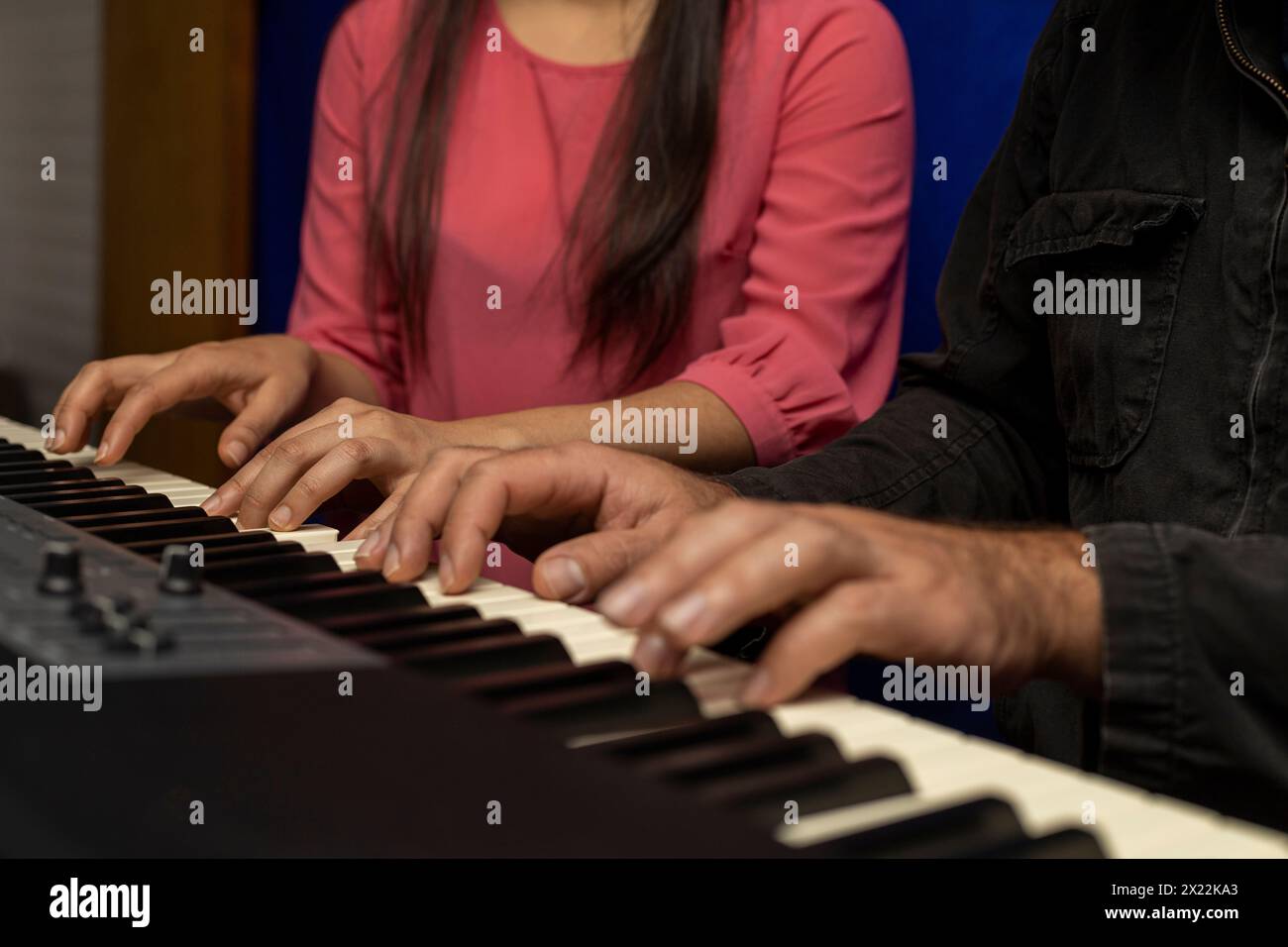 Professeur latino-américain joue du clavier de piano avec son élève à quatre mains. Concept de leçons de musique Banque D'Images