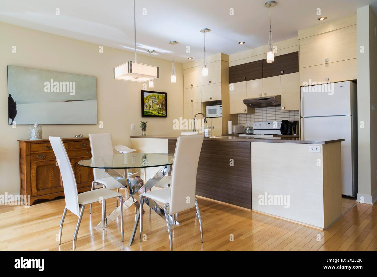 Salle à manger avec table ronde en verre, chaises à haut dossier en cuir blanc et cuisine à l'intérieur d'un appartement rénové au rez-de-chaussée dans un ancien résidentiel Banque D'Images