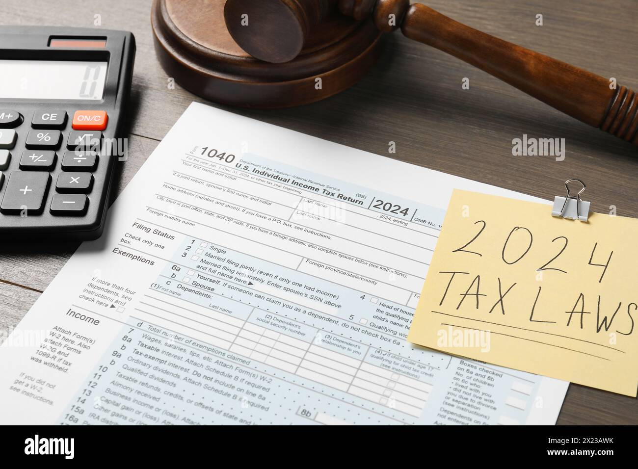 2024 lois fiscales. Formulaire, note papier, calculatrice et marteau sur table en bois, gros plan Banque D'Images