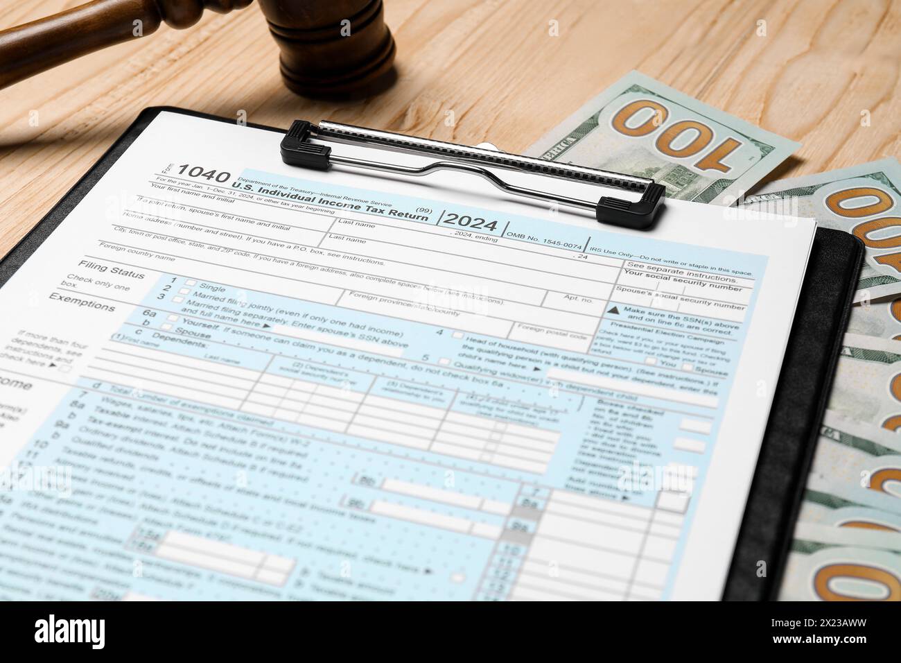 Presse-papiers avec formulaire de déclaration d'impôt, billets de banque en dollars et marteau sur la table en bois, gros plan Banque D'Images