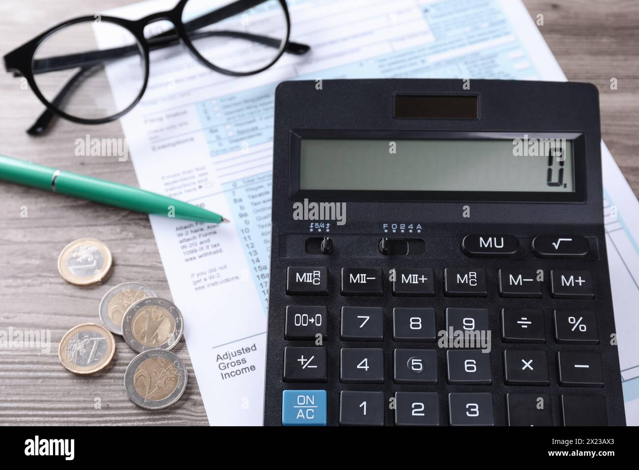 Comptabilité fiscale. Calculatrice, document, stylo et pièces de monnaie sur table en bois, gros plan Banque D'Images