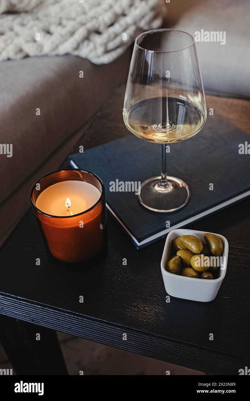 Bougie allumée, verre de vin blanc et olives sur la table Banque D'Images