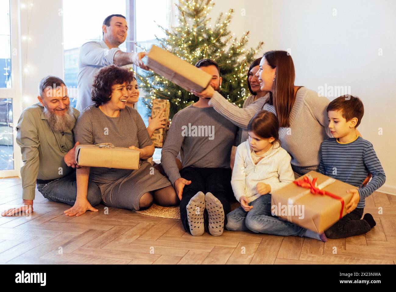 Une grande famille heureuse offre des cadeaux sous le sapin de Noël à la maison. Parents, grands-parents, enfants et petits-enfants célèbrent Noël ensemble. Rigolez Banque D'Images