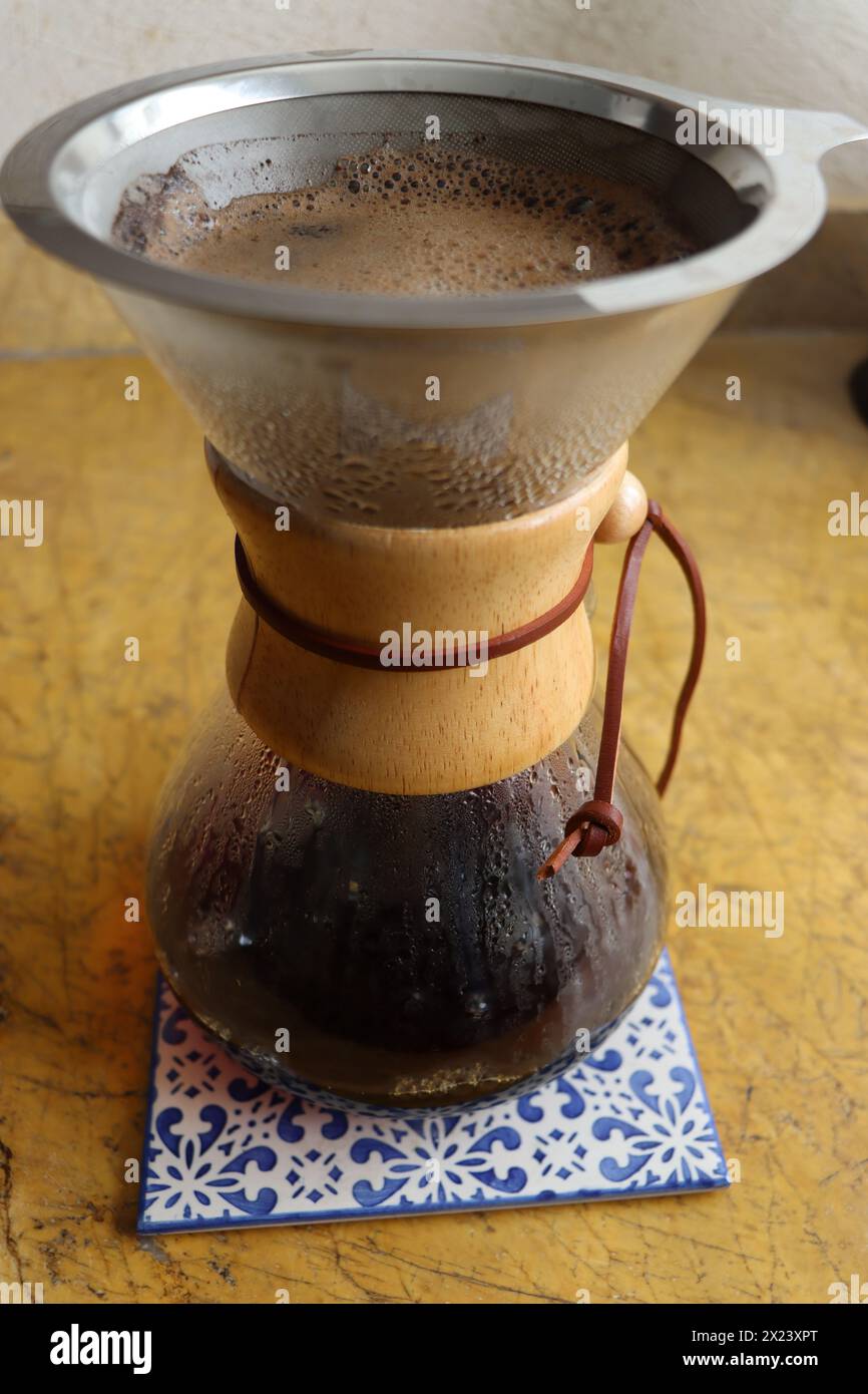 Versez le verre sur la cafetière sur le carreau de céramique. Plan vertical, complet, sans personne, verser sur la cafetière avec du café fraîchement infusé Banque D'Images