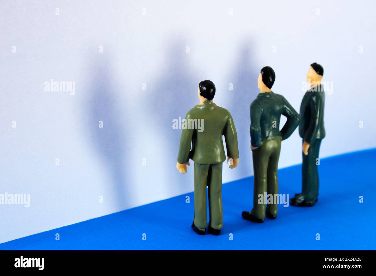 Trois personnes face à un mur projetant leur ombre Banque D'Images