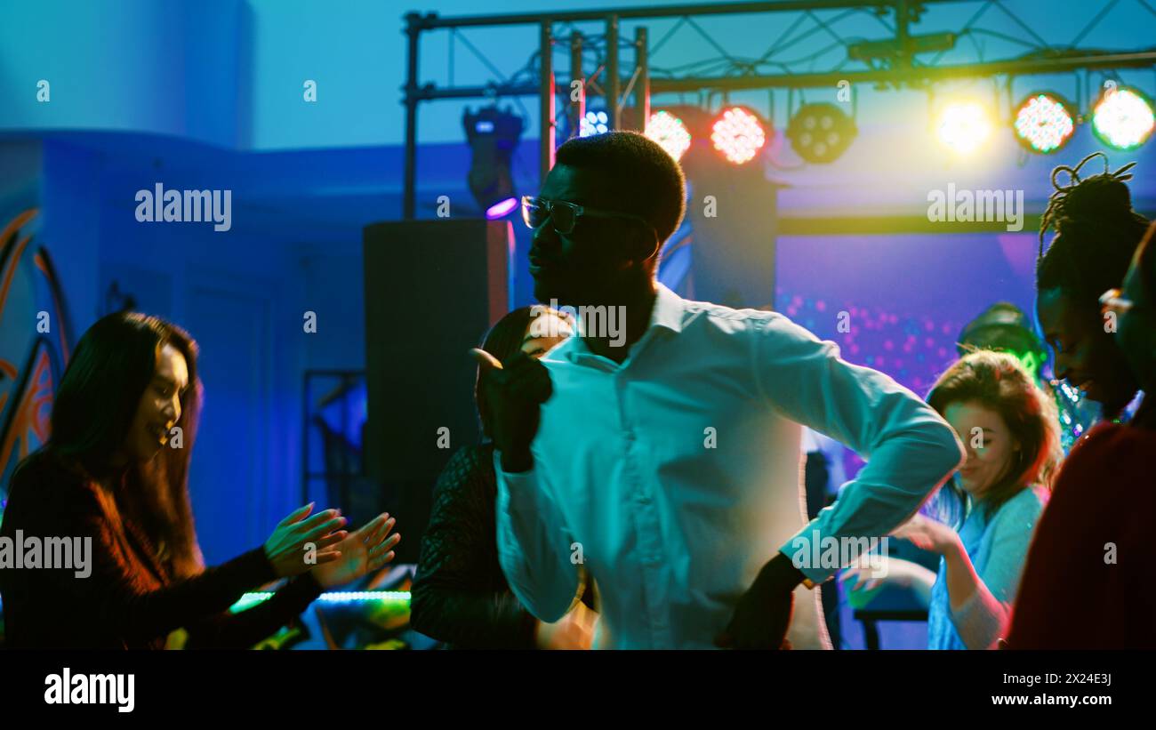 Jeunes faisant la fête à la discothèque s'amusant et buvant de l'alcool au bar, amis énergiques dansant et profitant de la vie nocturne. Personnes faisant la fête sur la piste de danse, funky clubbing. Banque D'Images