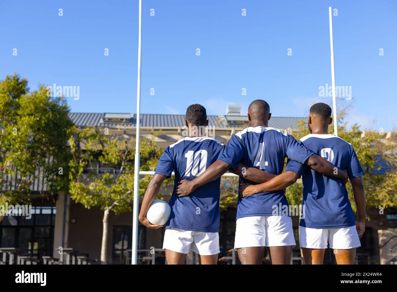 Trois jeunes athlètes afro-américains portant des maillots bleus, debout sur un terrain de rugby en plein air Banque D'Images