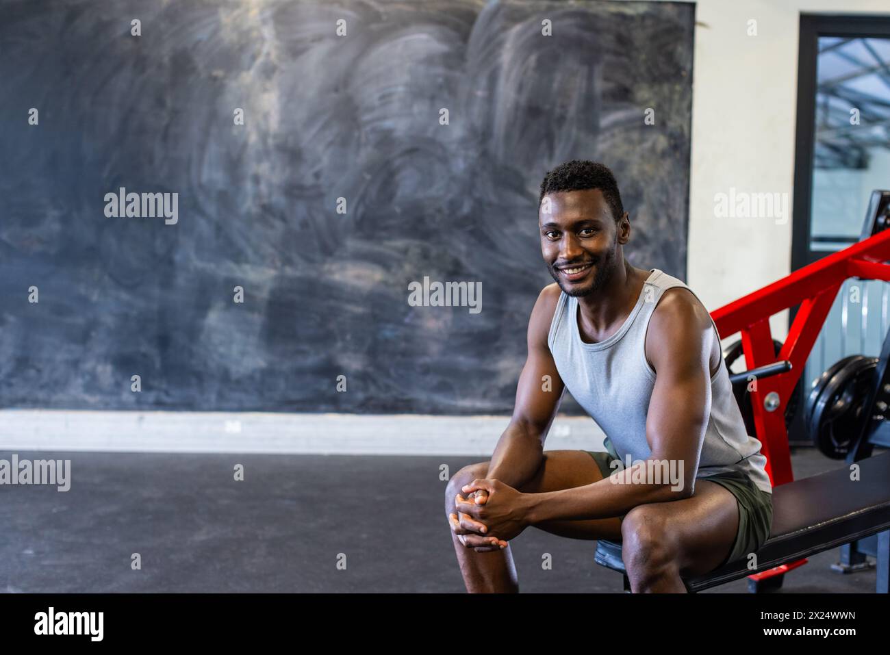 Jeune athlète afro-américain assis sur un banc dans un gymnase, souriant, espace de copie Banque D'Images