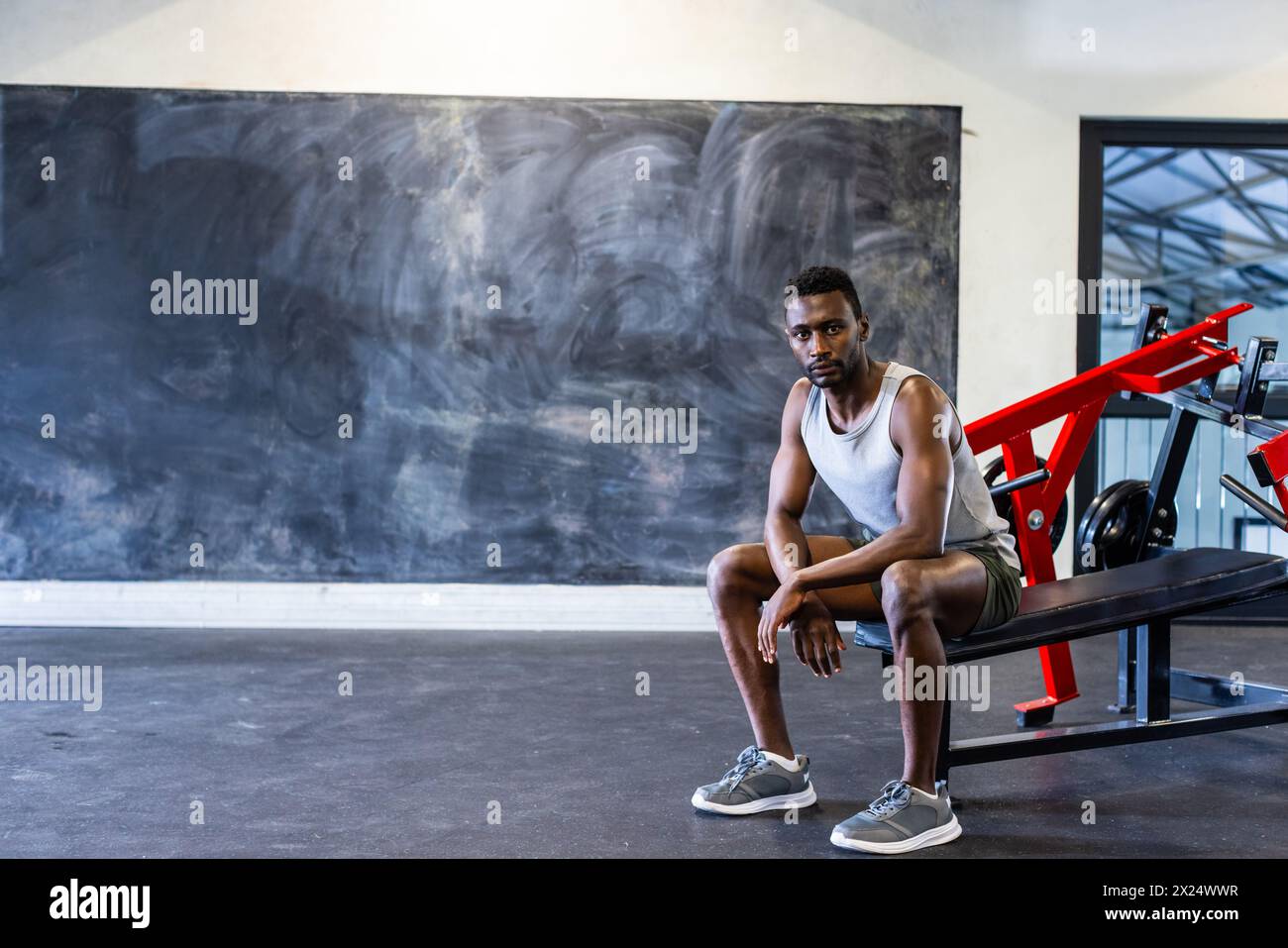Jeune athlète afro-américain assis sur un banc dans une salle de gym, se reposant, espace de copie Banque D'Images