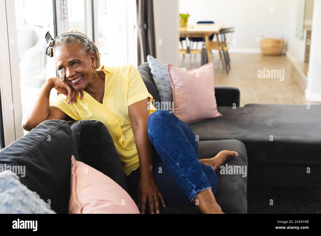 Femme aînée afro-américaine assise sur un canapé à la maison, regardant heureux, espace de copie Banque D'Images
