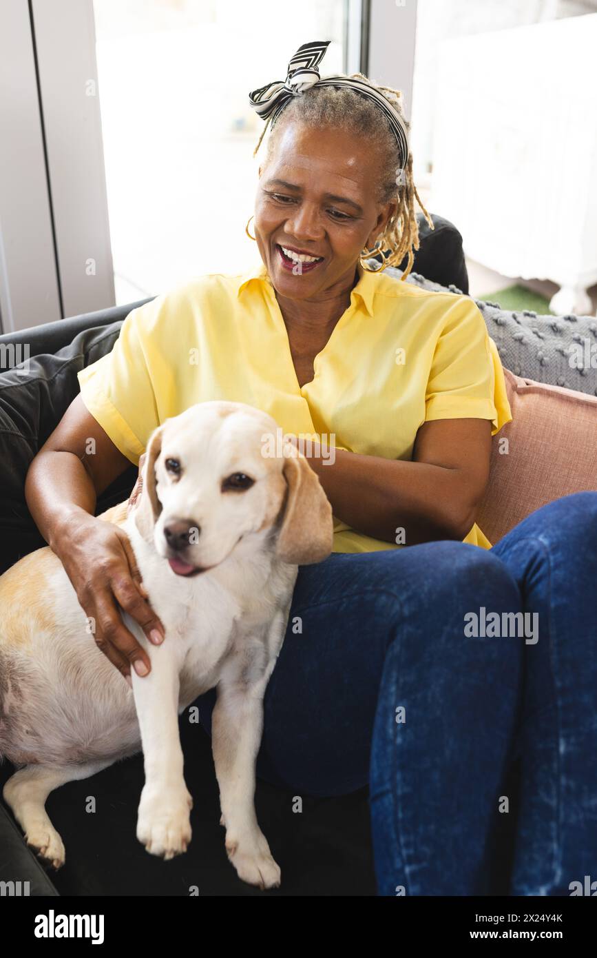 Une femme afro-américaine âgée caresse son chien à la maison Banque D'Images