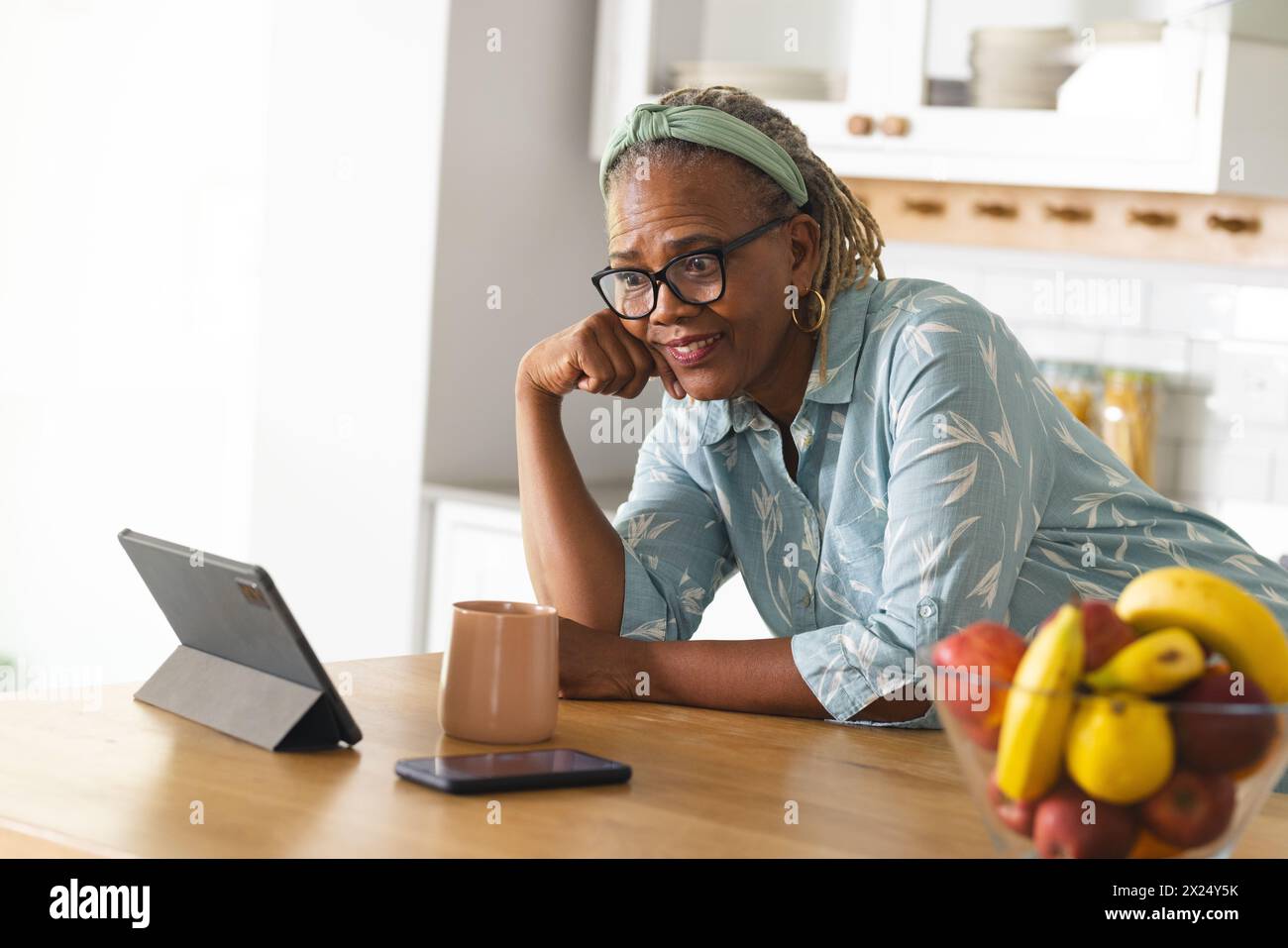 Une femme afro-américaine senior portant des lunettes regardant une tablette à la maison Banque D'Images