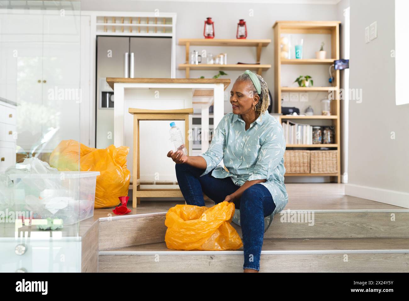 Femme aînée afro-américaine triant le recyclage à la maison Banque D'Images
