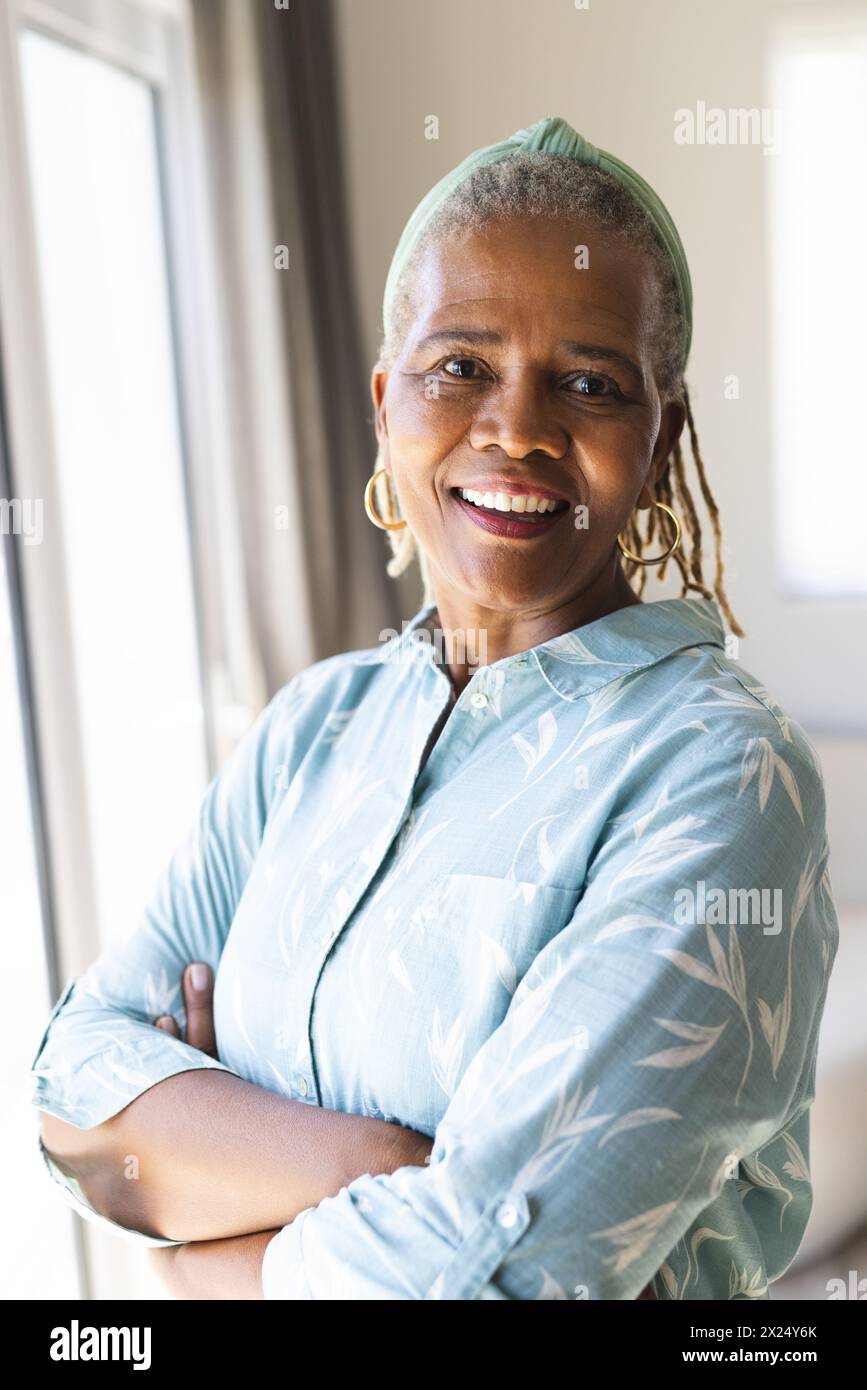 Femme aînée afro-américaine debout, les bras croisés, souriant à la maison Banque D'Images