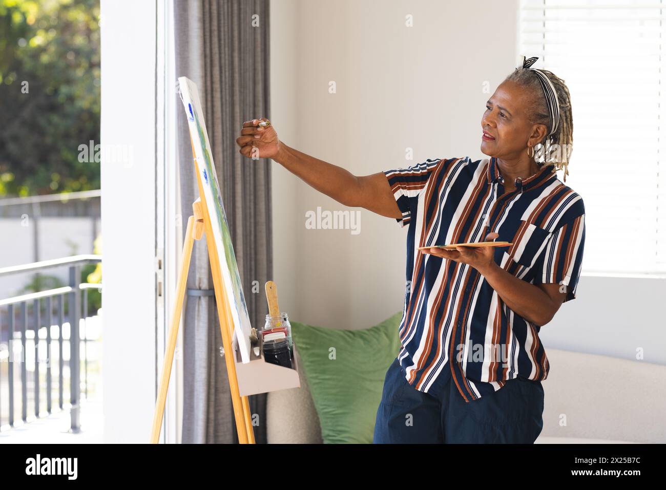 Une femme afro-américaine senior peint sur toile à la maison Banque D'Images