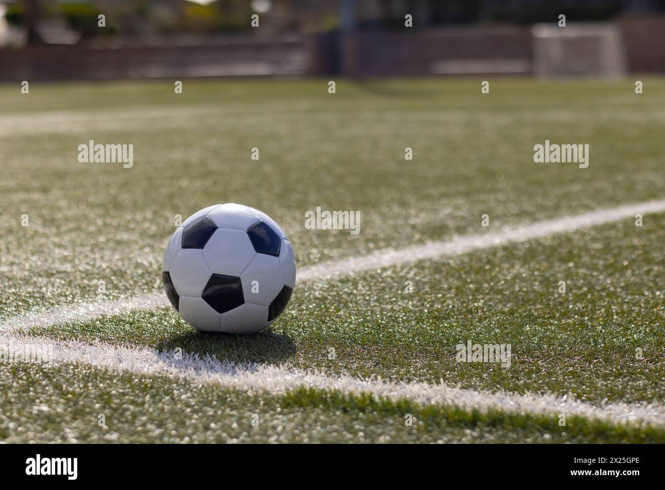 Un ballon de football reposant sur un gazon artificiel vert près de la ligne blanche sur le terrain à l'extérieur, espace de copie Banque D'Images