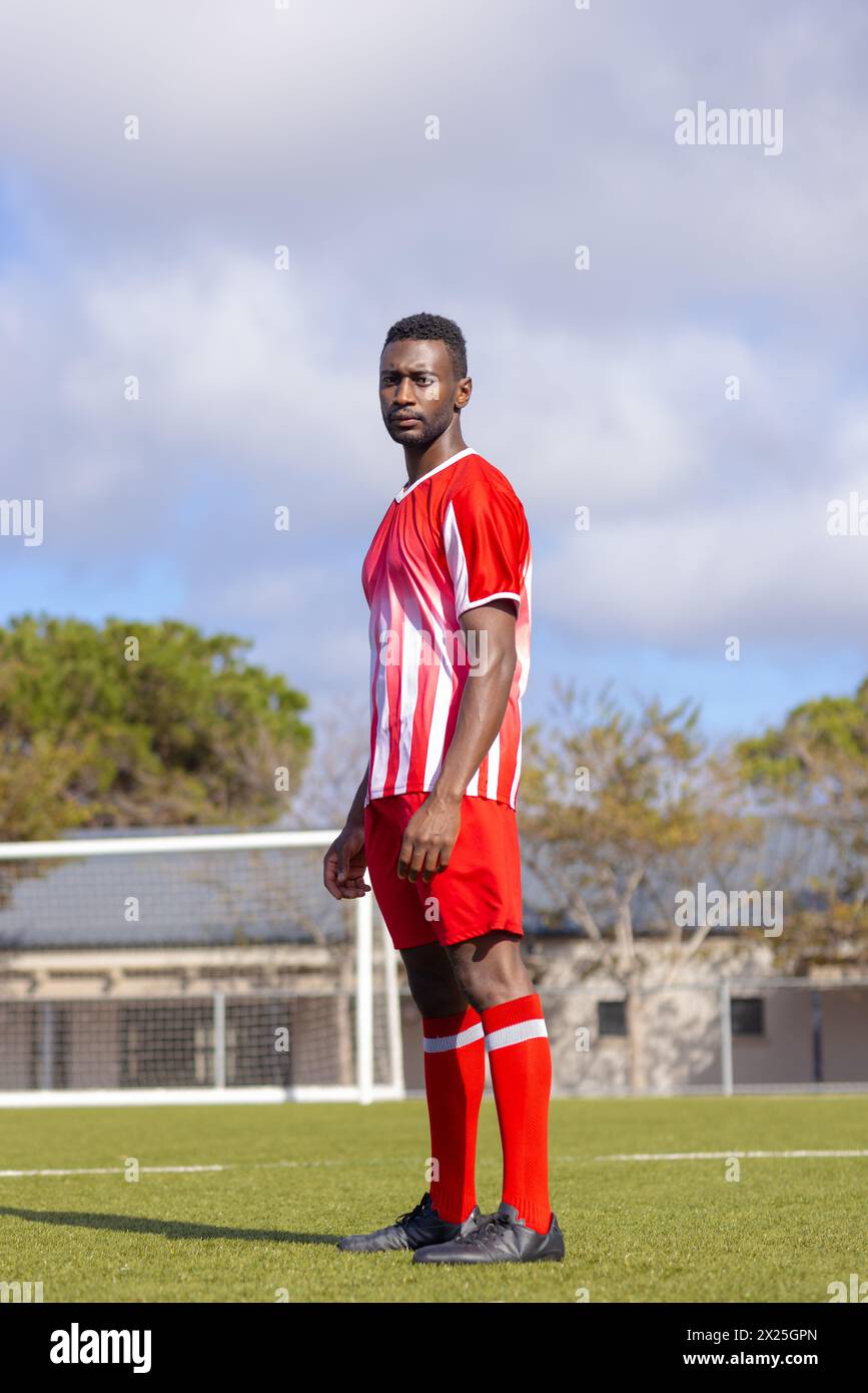 Athlète masculin noir en rouge et blanc sur le terrain de football Banque D'Images
