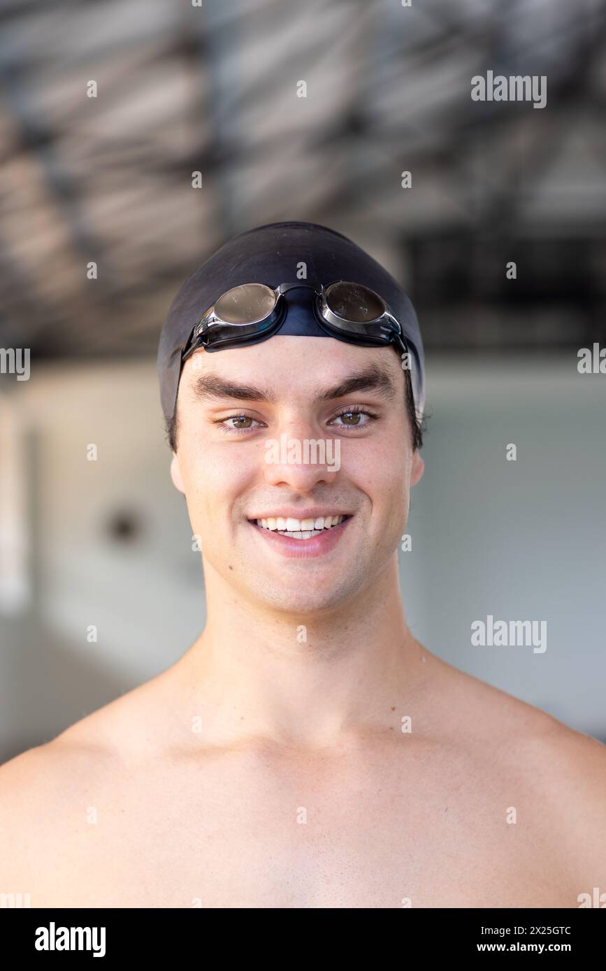 Jeune nageur caucasien souriant à l'intérieur, portant des lunettes sur la tête Banque D'Images