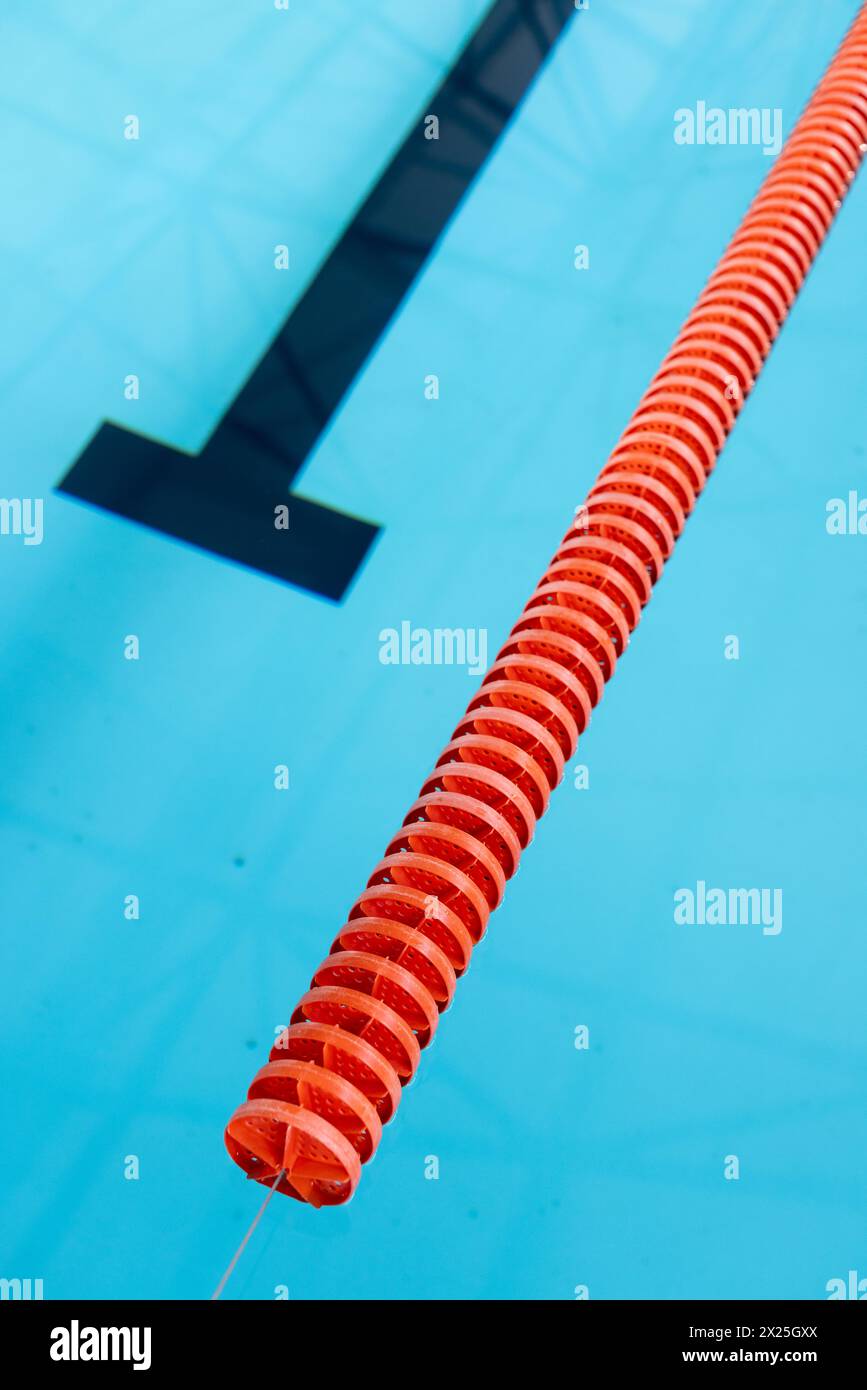 Un séparateur de voie rouge et blanc flotte dans une piscine intérieure bleue, espace copie Banque D'Images