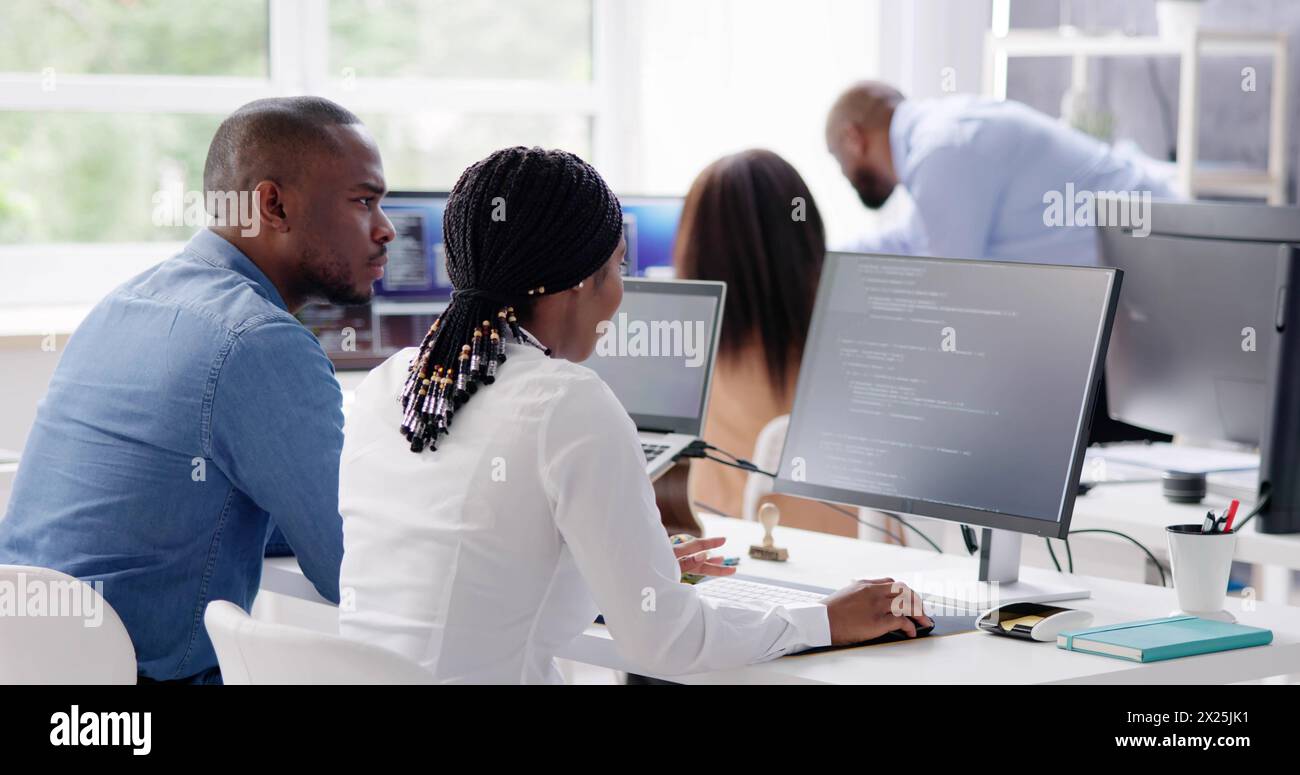 Équipe d'affaires africaine de programmeurs codant sur ordinateur Banque D'Images