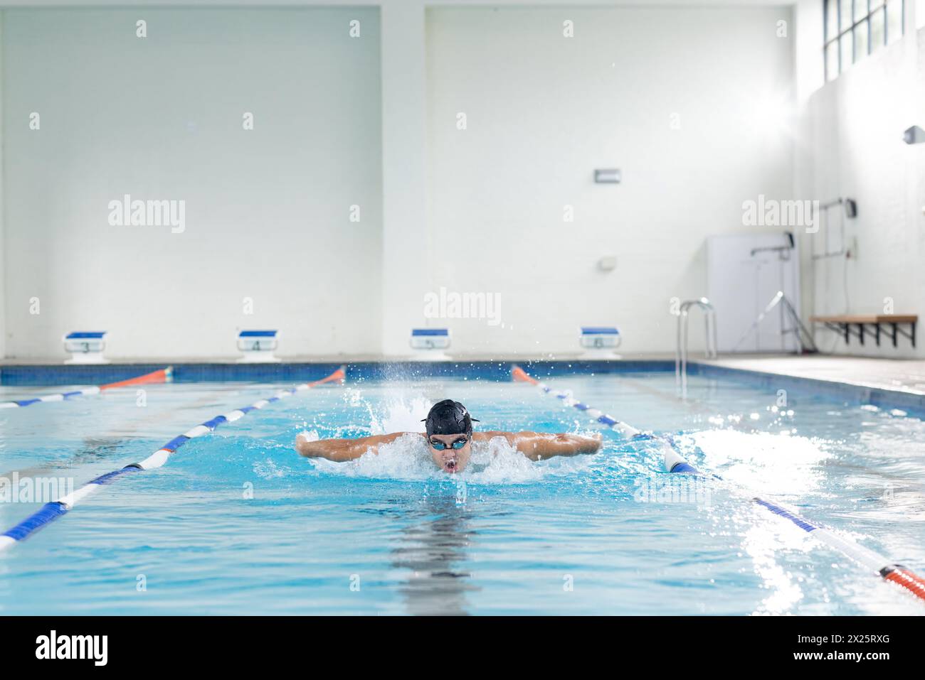 Jeune nageur masculin caucasien s'entraînant à l'intérieur dans une piscine intérieure, portant des lunettes de protection, espace de copie Banque D'Images